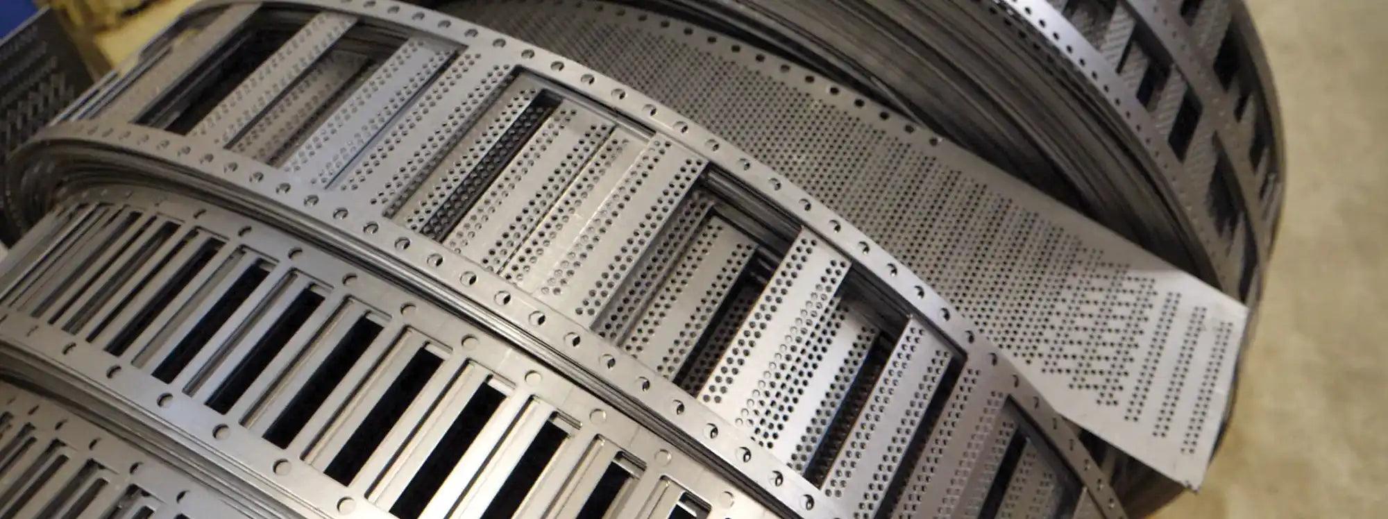 Curved metal structure with perforated panels and vertical slats.